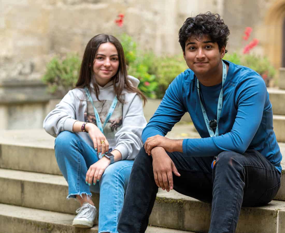 Male and female student smiling and sitting on the steps outside Oxford College at 澳洲五号码结果 Summer Boarding Courses