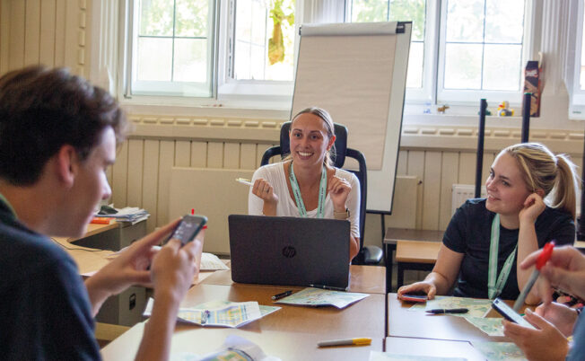 Summer Boarding Courses Social Programme Manager talking to her team in a classroom