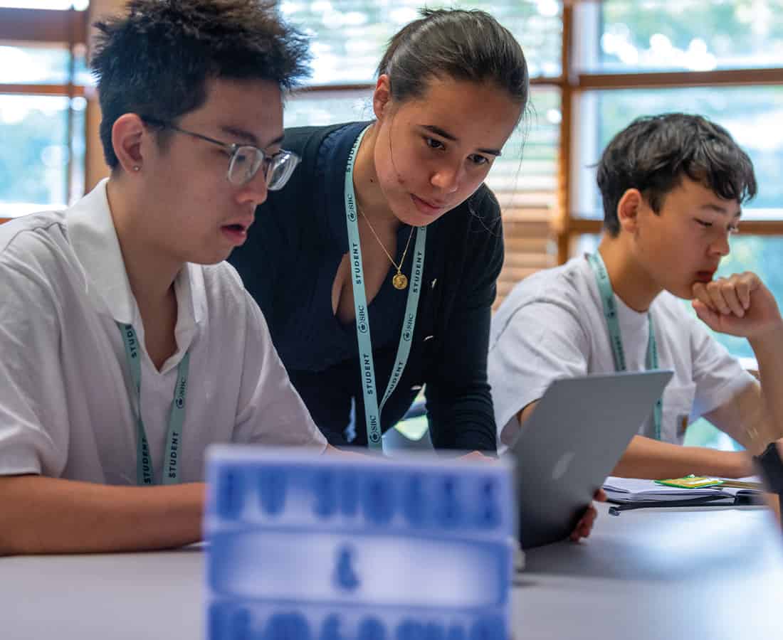 Three students in an academic class at Summer Boarding Courses, they are concentrating and working on their laptops together