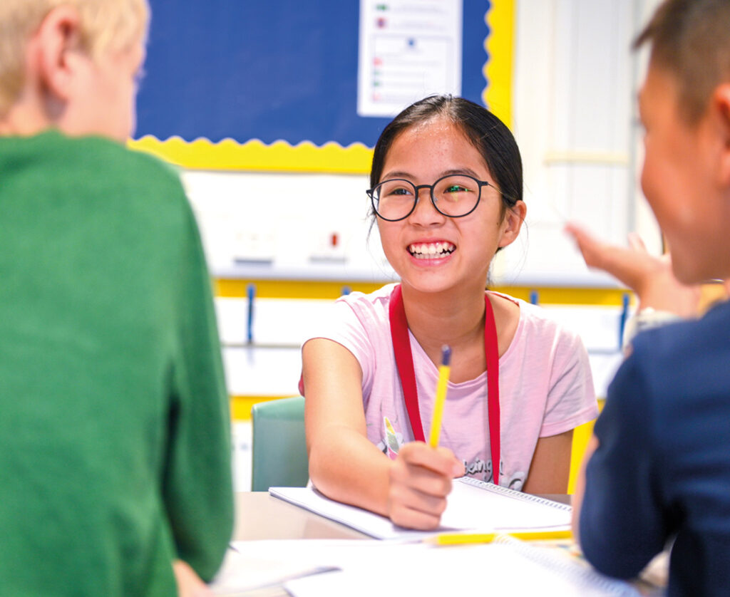 Young Female Student Engaging with Her Classmates and Smiling at Camp Dragon