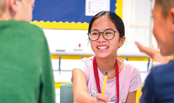 Young Female Student Engaging with Her Classmates and Smiling at Camp Dragon